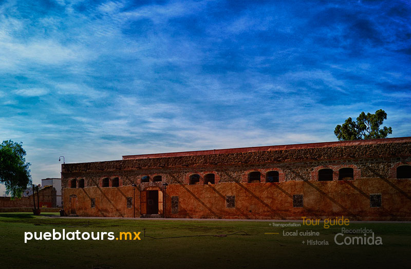 Larga fachada de la Ex Hacienda de Chautla de ladrillo bajo un cielo azul