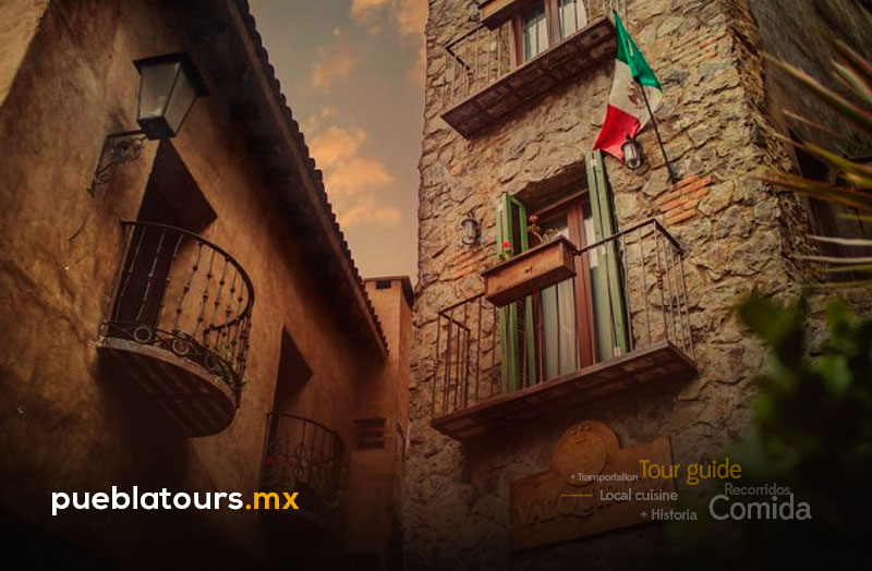 Callejón de Val’Quirico con balcones de hierro y bandera de México