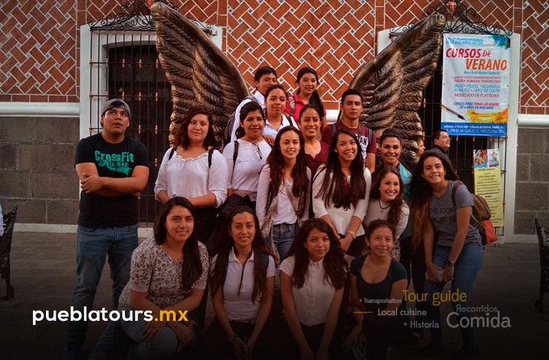 Grupo de viajeros posando junto a alas y muro de ladrillo en El Parián